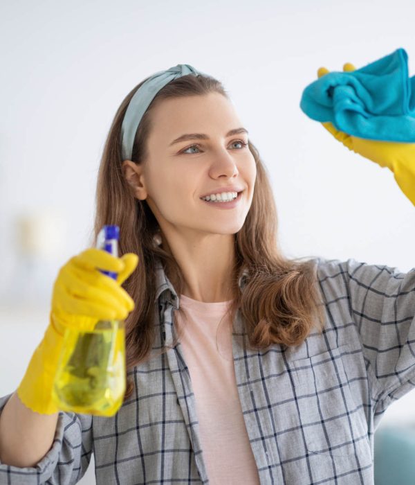 Happy professional cleaner smiling while holding a blue microfiber cloth wearing yellow gloves